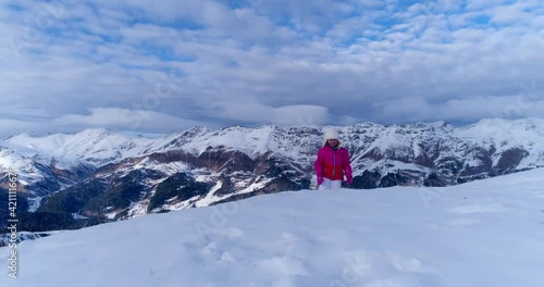 Happy little girl climbs the snowy mountain peak