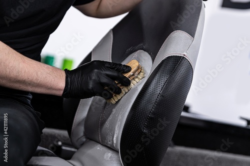 Obraz na płótnie Man car wash worker cleaning leather boat seat with brush and detergent w salonie