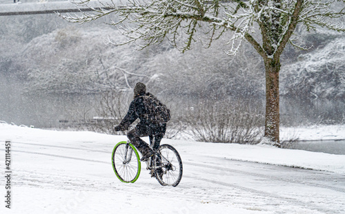 Duringa snow storm, a man riding a bicycle in riverfront park, salem, Oregon