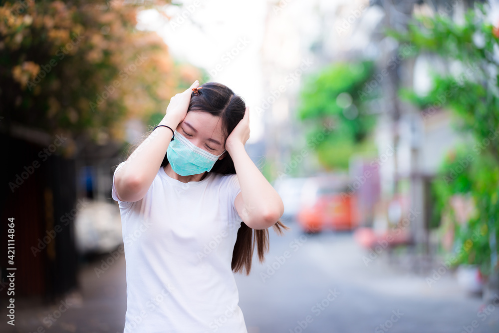 Upset sad Asian beautiful woman suffering from headache. Standing on road alone. Holding head in hands. Upset person has psychological troubles. Thinking about problem in virus disease - air pollution