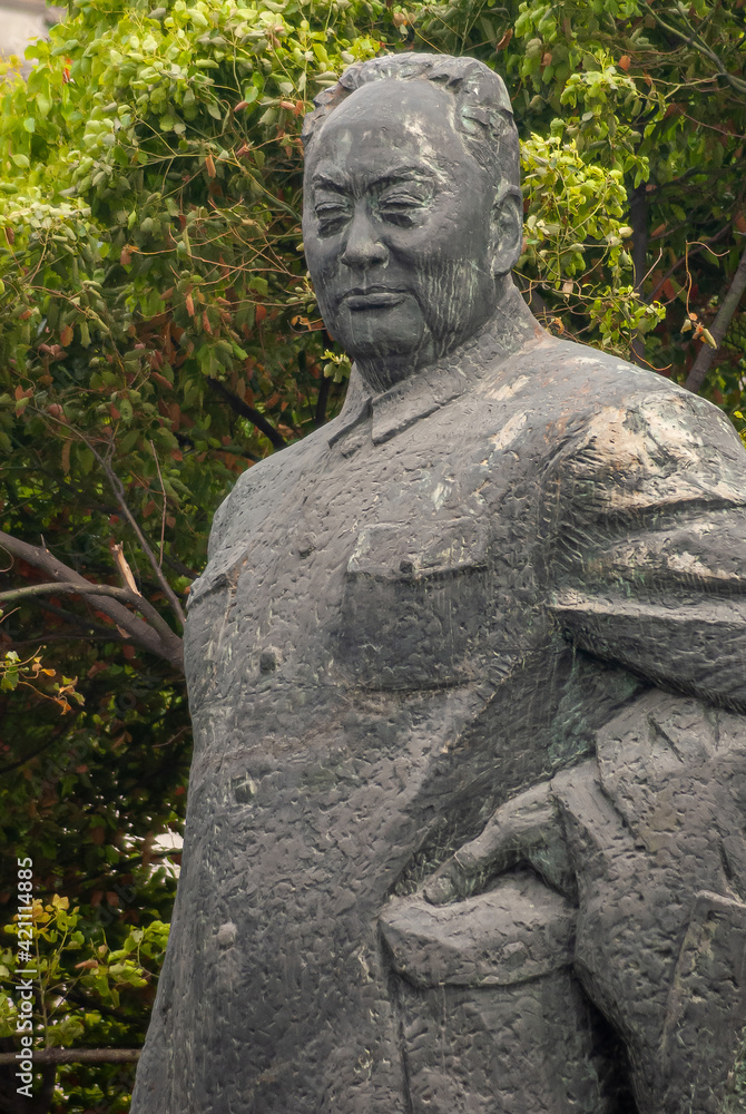 Shanghai, China - May 4, 2010: Facial closeup of  Chen Yi gray statue. Green foliage as backdrop. 