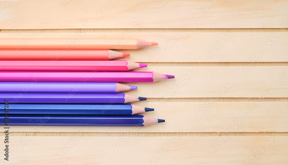 Fototapeta premium Composition with pink, purple and blue pencils on wood background, top view