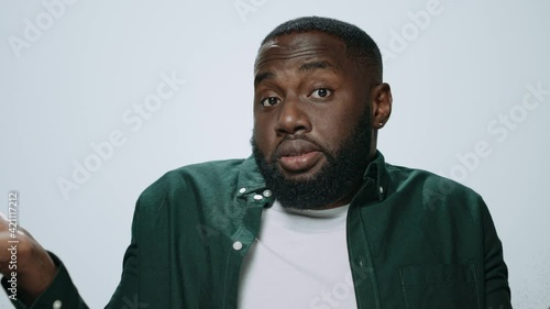 Portrait of african american man showing dont know gesture on grey background.