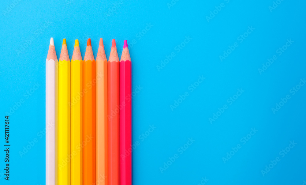 Composition with colored pencils on blue background, top view Composition with colored pencils on blue background, top view