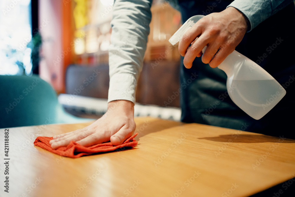 Dust cleaning agent. disinfection with a special agent against virus, microbes, infection. spray cleaning of the cafe before the arrival of guests. Wipes the table with a rag in a restaurant.