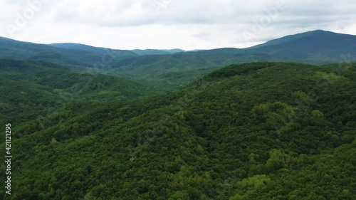Flying over green mountain peaks on a spring day