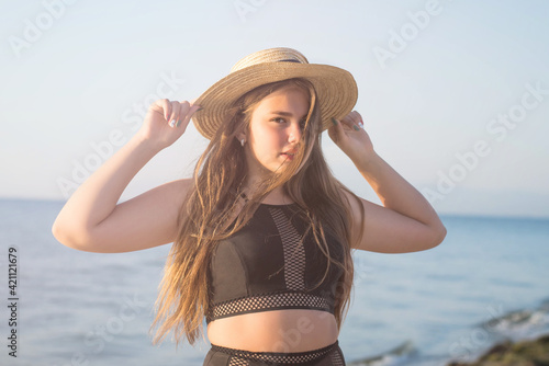Cheerful plus size teenage girl wearing hat enjoying the beach. smiling, happy, positive emotion, summer style. © MartaKlos