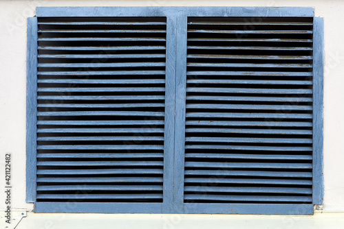 A blue ventilation grate on a white brick wall. Detail