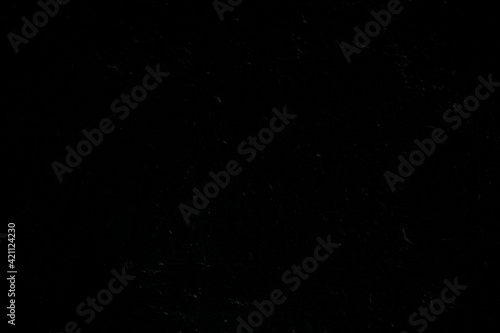 Close-up of an uneven dark gray, almost black, painted concrete wall. Dark high resolution full frame textured background.