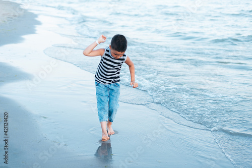 Cute little boy listening sound of sea in shell at the beach.