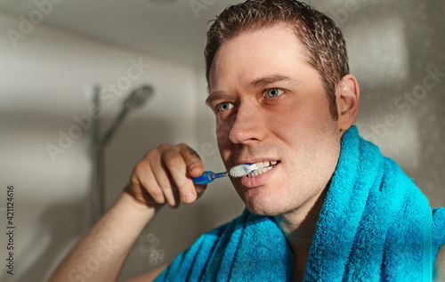 Man brushes his teeth in the bathroom.