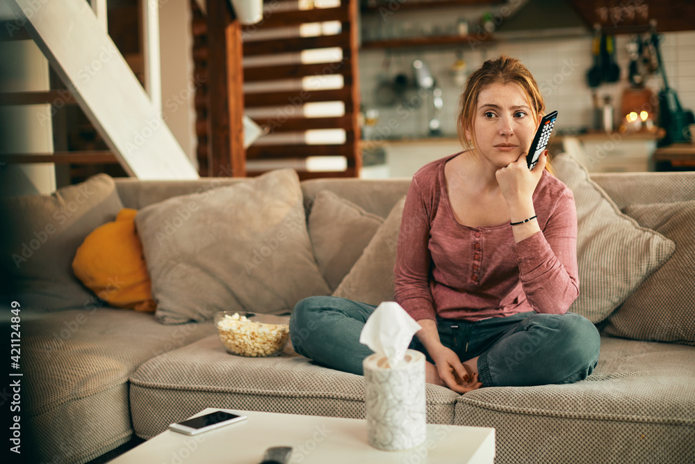 Obraz premium Young woman watching sad movie on TV in the living room.