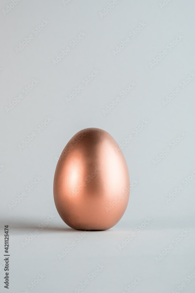 Big Rose gold color Easter egg on a simple gray background. Main christian holiday backdrop. Big Rose gold color Easter egg on a simple gray background. Main christian holiday backdrop.