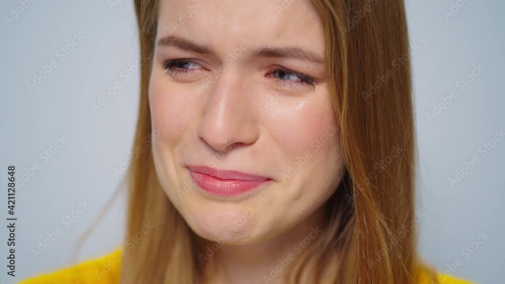 Crying woman smiling at camera on grey background in studio. Sad and happy Crying woman smiling at camera on grey background in studio. Sad and happy