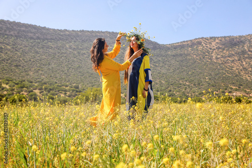 Two women with wreath in a field.
