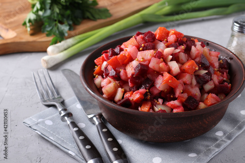 Fototapeta Naklejka Na Ścianę i Meble -  Traditional Russian salad Vinaigrette with beets, carrots, potatoes and onions in a clay bowl on light gray background. Vegetarian food. Closeup.