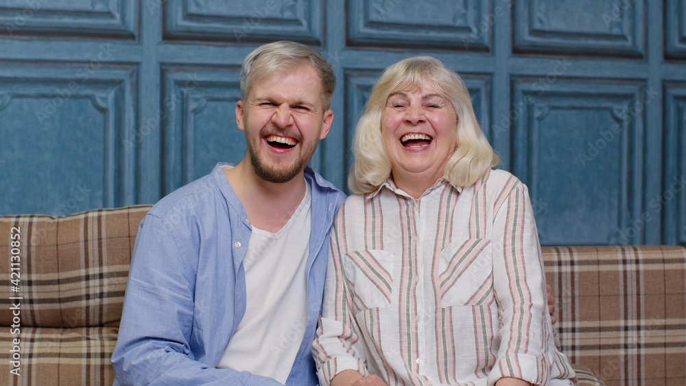 Happy senior older mother and smiling young adult grown son hugging laughing looking at camera Happy senior older mother and smiling young adult grown son hugging laughing looking at camera