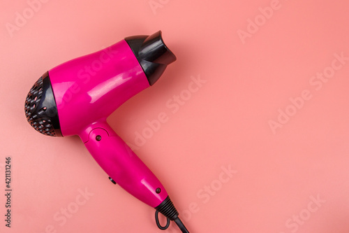 Pink hair dryer on a pastel pink background. Top view