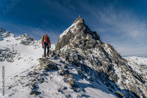 An alpinist climbing in winter alpine like landscape of High Tatras, Slovakia. Winter mountaineering in snow, ice and rock. Alpinism, high peaks and summits with snow and ice.
