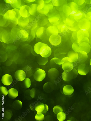 background of defocused green lights in circular shape in sunlight, from dark to light