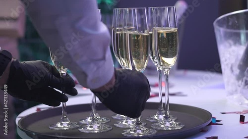 the waiter puts glasses of champagne on a tray at a wedding party