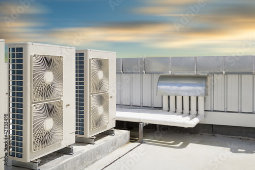 Condenser unit or compressor on roof of industrial plant building with sky background. Unit of central air conditioner (AC) or heating ventilation air conditioning system (HVAC). Pump and fan inside. photo