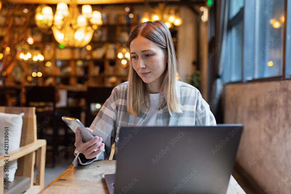 Young Caucasian business woman with blonde hair working on laptop in cafe. College student using technology , online education, freelance Young Caucasian business woman with blonde hair working on laptop in cafe. College student using technology , online education, freelance