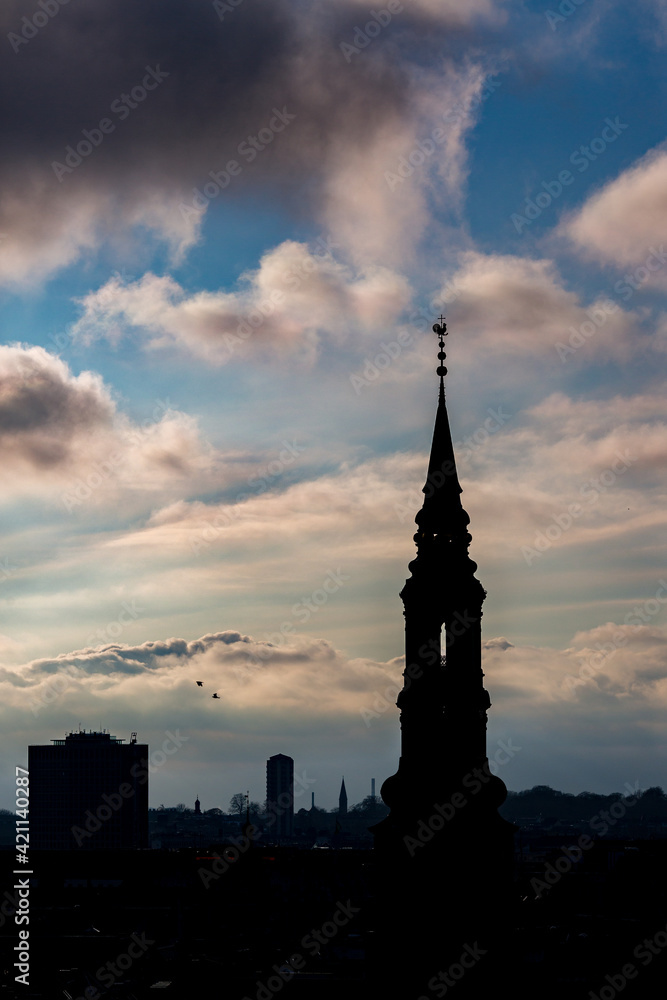 Cityscape, amazing silhouettes view over the city of Copenhagen, Denmark. Winter cloudy dark moody picturesque scene. Picture taken from Round Tower. Church tower
