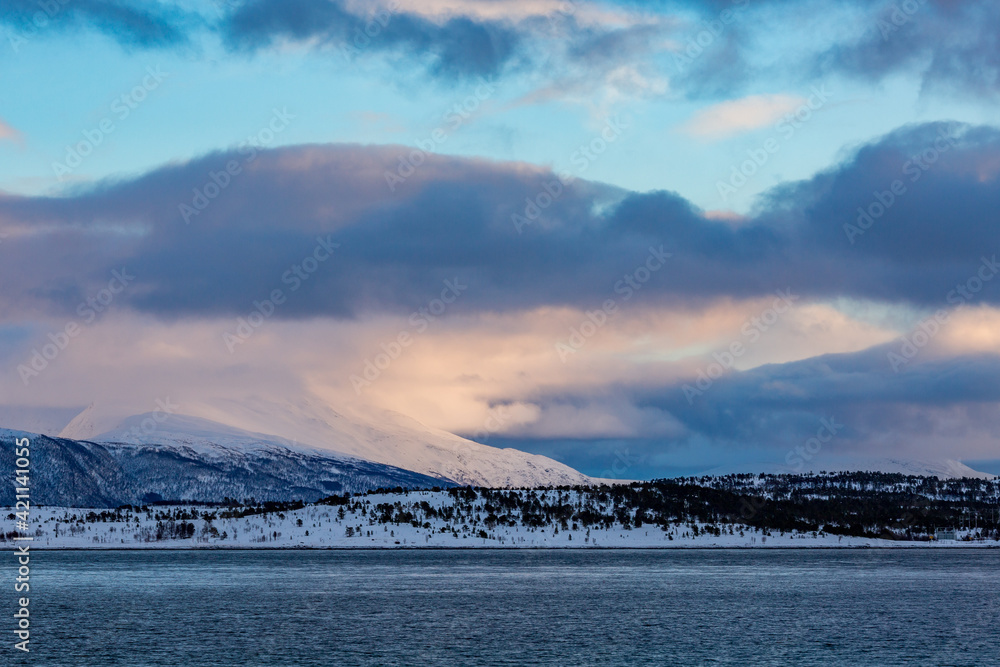 Northern Norway, winter cloudy landscape with fjords covered in snow. Scene near Tromso, colorful polar evening puffy clouds