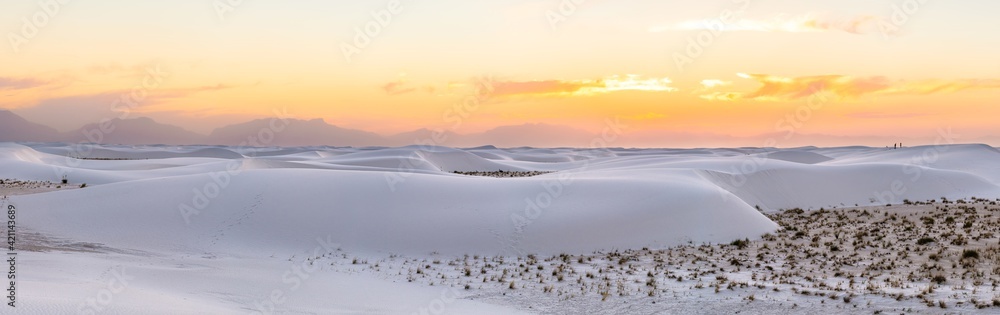 Panorama panoramic view of Organ mountains silhouette at White sands national park monument sand dunes and plants in New Mexico at colorful orange yellow sunset