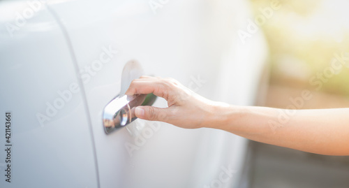 Female hand of a business woman with a pushing open botton of the car door.