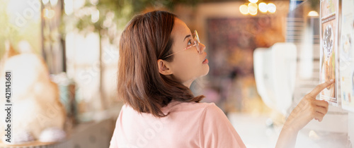 Female hand pointing at the menu for choosing eating at the coffee shop, Due to the Covid-19 customer will choose with the transparent acrylics, and social distancing .