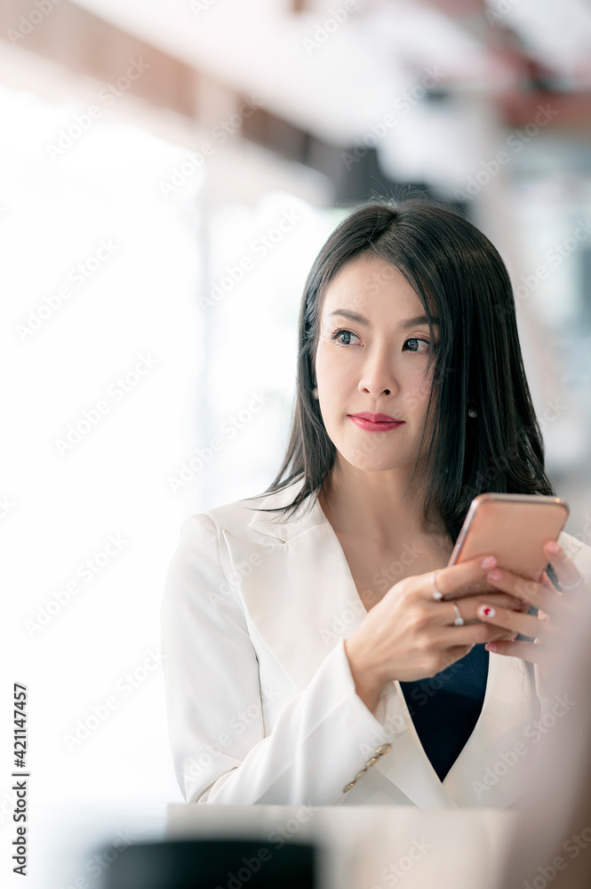 Portrait of young beautiful asian woman using smartphone while sitting in office. Portrait of young beautiful asian woman using smartphone while sitting in office.