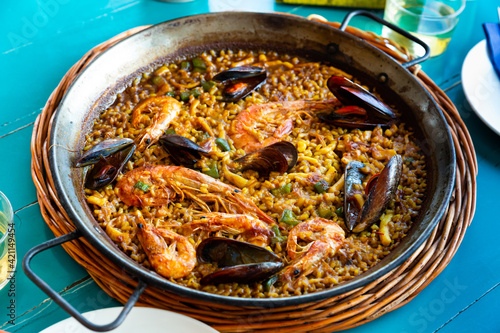 Freshly made paella with assorted seafoods served in frying pan on wooden table