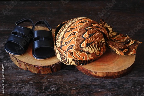 a set of traditional clothing from Central Java Indonesia consisting of a shirt, pants, a blangkon hat and sandals. photo