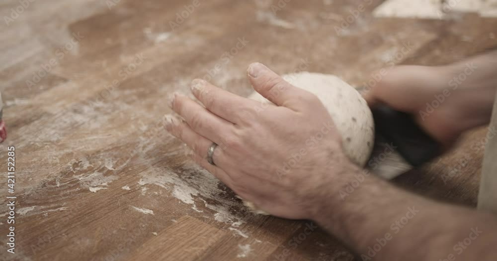 Male baker working in bakery kneading fresh dough on kitchen counter Male baker working in bakery kneading fresh dough on kitchen counter
