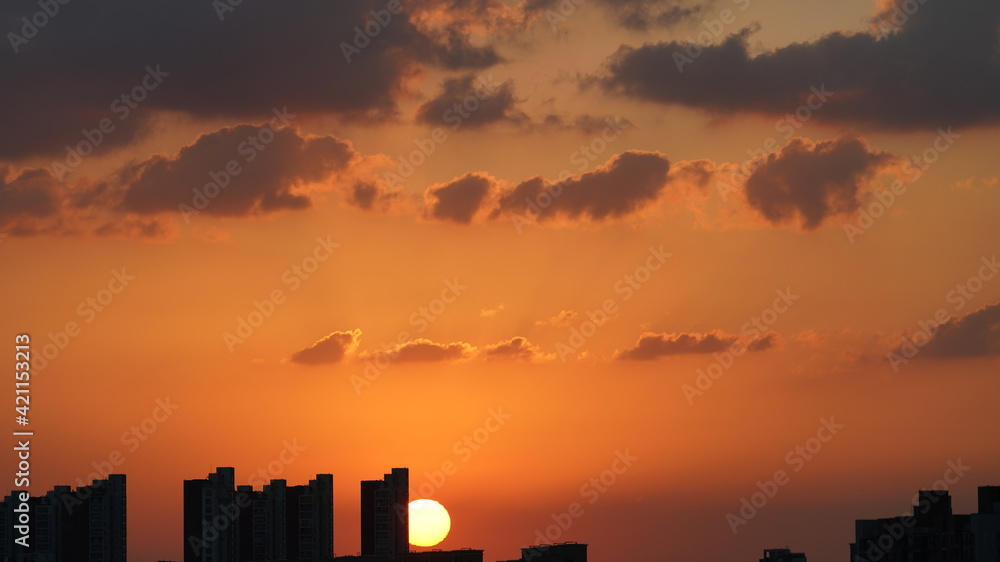 Fototapeta premium The beautiful sunset view with the round sun and the colorful clouds in the sky