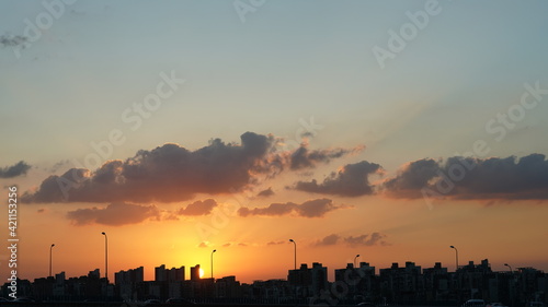 The beautiful sunset view with the round sun and the colorful clouds in the sky
