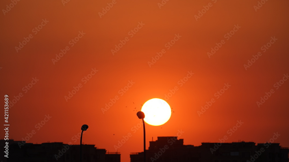 The beautiful sunset view with the round sun and the colorful clouds in the sky The beautiful sunset view with the round sun and the colorful clouds in the sky