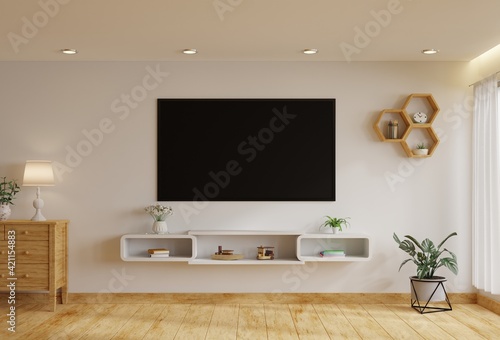 TV in the living room on a white wall by the window, decorated with plants, vases, flowers, toys and lamps.3d rendering.