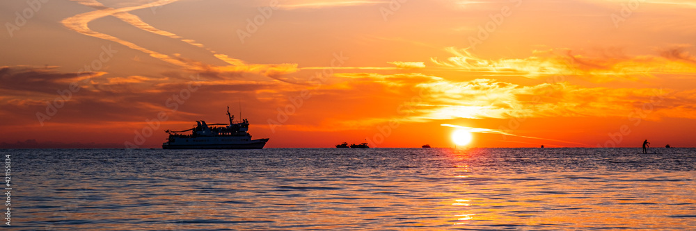 Beautiful sunset on the sea coast. The sun reflecting on the sea. Nature background. Banner.