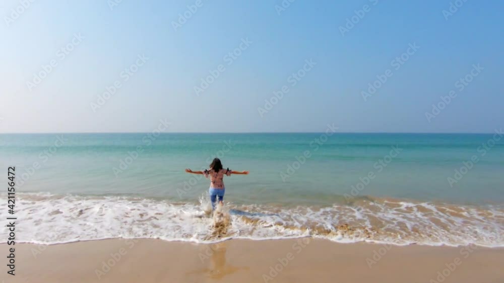 Young carefree happy woman running towards ocean with open arms. Summer Holiday at tropical beach Young carefree happy woman running towards ocean with open arms. Summer Holiday at tropical beach