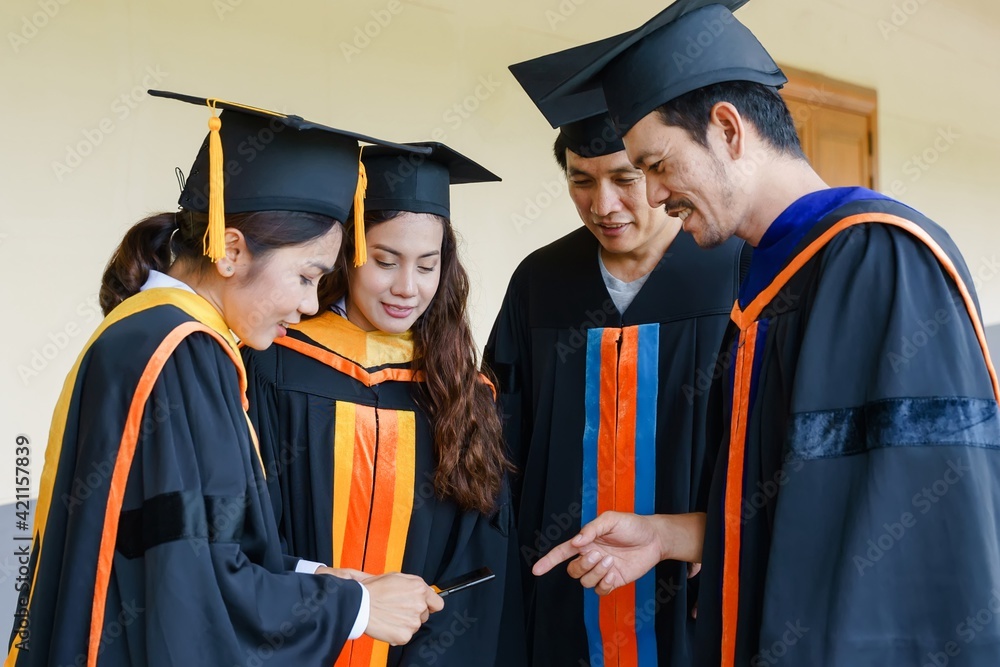 The university graduates in graduation gown and a mortarboard cap with a degree certificate in hand celebrating education achievement in the commencement ceremony. Congratulations to the graduations The university graduates in graduation gown and a mortarboard cap with a degree certificate in hand celebrating education achievement in the commencement ceremony. Congratulations to the graduations
