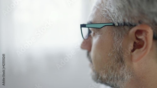 Extreame close up shot slow motion of old man looking out of the windows with worried expression.
