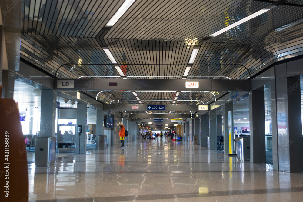 An almost empty airport terminal with a few people at the far end. An almost empty airport terminal with a few people at the far end.