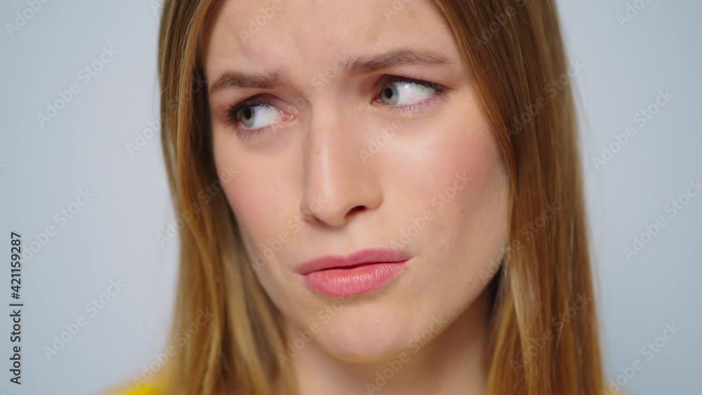 Closeup worried woman looking at camera on grey background in studio. Closeup worried woman looking at camera on grey background in studio.