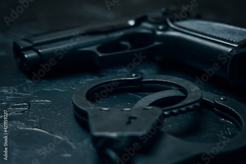 Firearms and handcuffs close up on black table. Gun for law enforcement. Ammunition for the arrest of criminals.