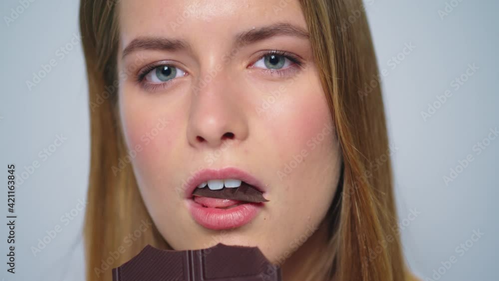 Closeup sensual woman enjoying chocolate at camera on grey background. Closeup sensual woman enjoying chocolate at camera on grey background.
