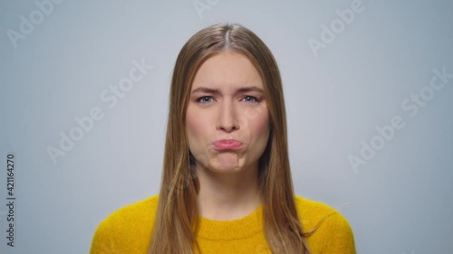 Portrait of beautiful girl making grimaces at camera on grey background.