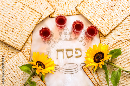 Pesah celebration concept - Jewish Passover holiday. Unleavened bread food - matzoh, glasses of red wine. and sunflowers. Three Hebrew letters, in English translation mean Jewish Passover photo